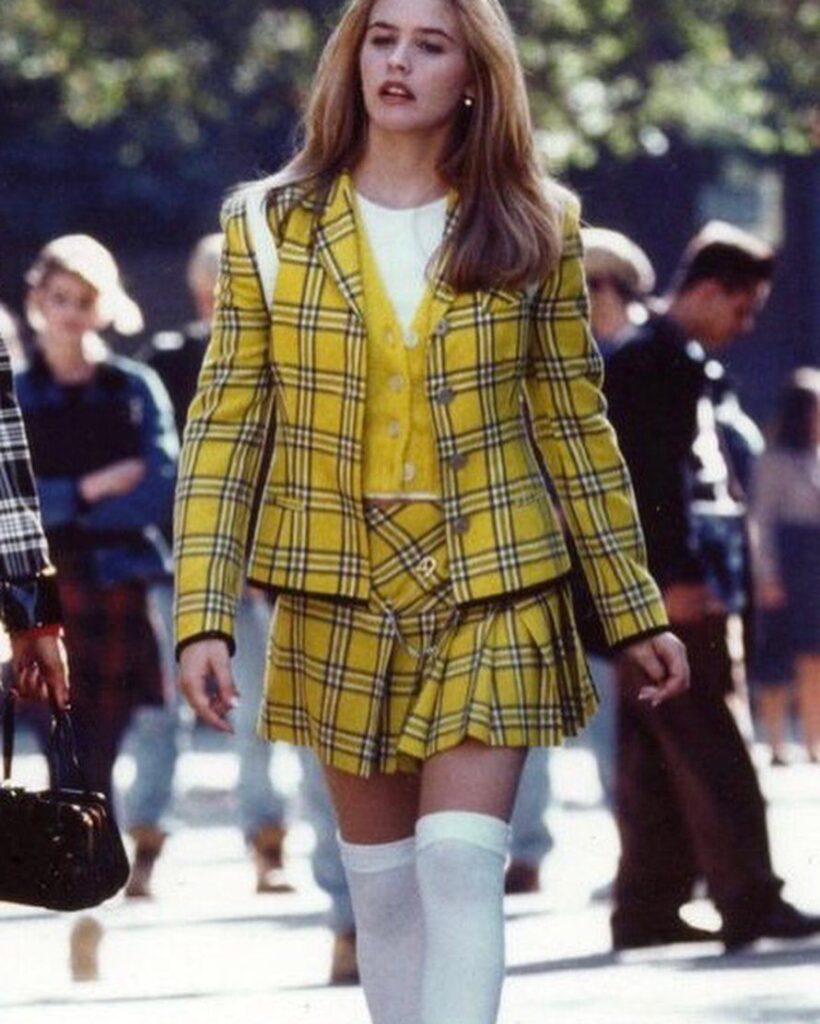 Woman wearing a yellow plaid blazer and matching skirt with white knee-high socks.
