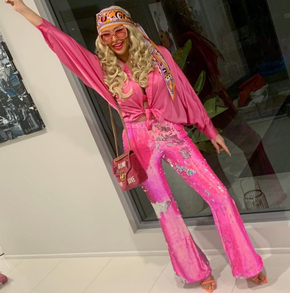 Person in pink sequined flared pants and matching top posing for a disco look.
