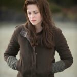 Woman wearing a brown hooded jacket and grey knit gloves in a natural setting.