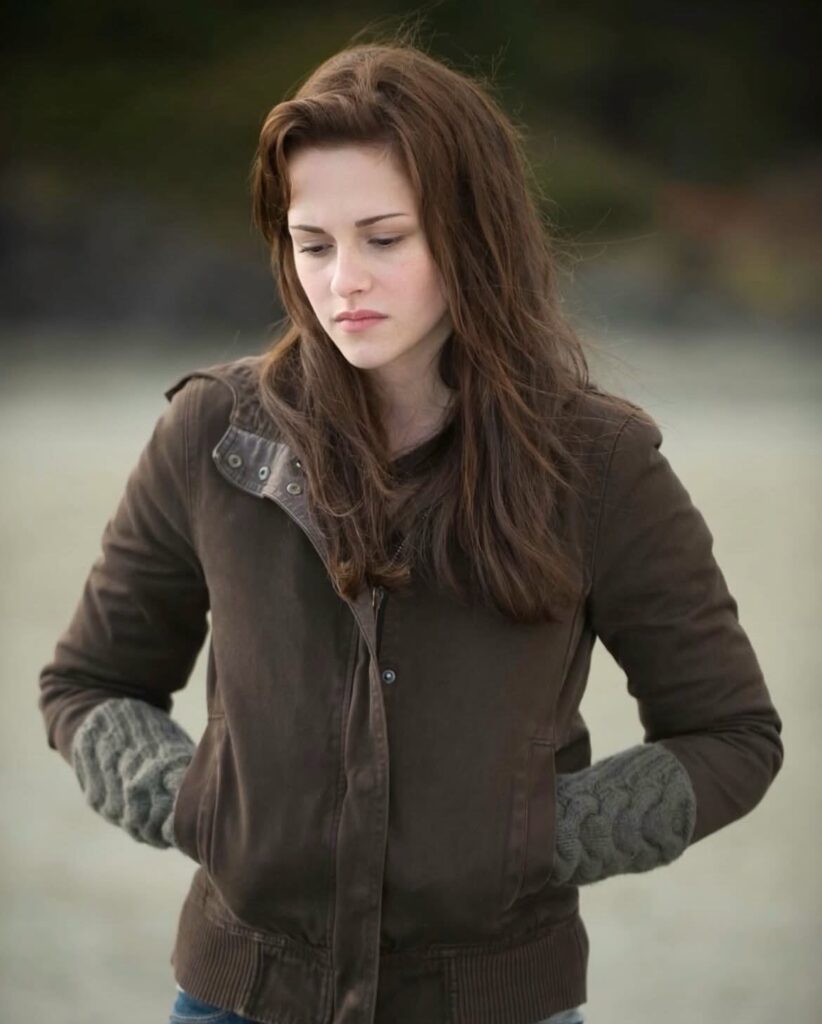 Woman wearing a brown hooded jacket and grey knit gloves in a natural setting.