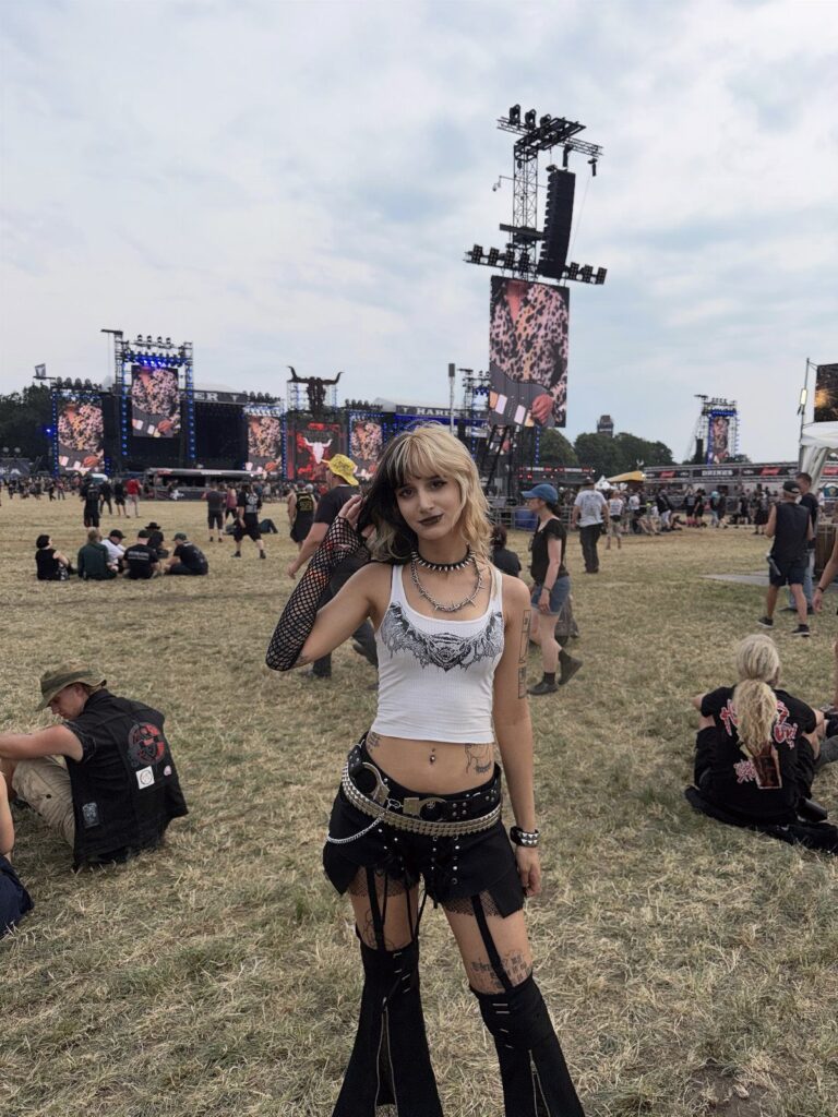 Woman in edgy concert attire with a white crop top and black studded accessories.