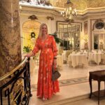 Woman in orange floral maxi dress posing in a luxury hotel dining room