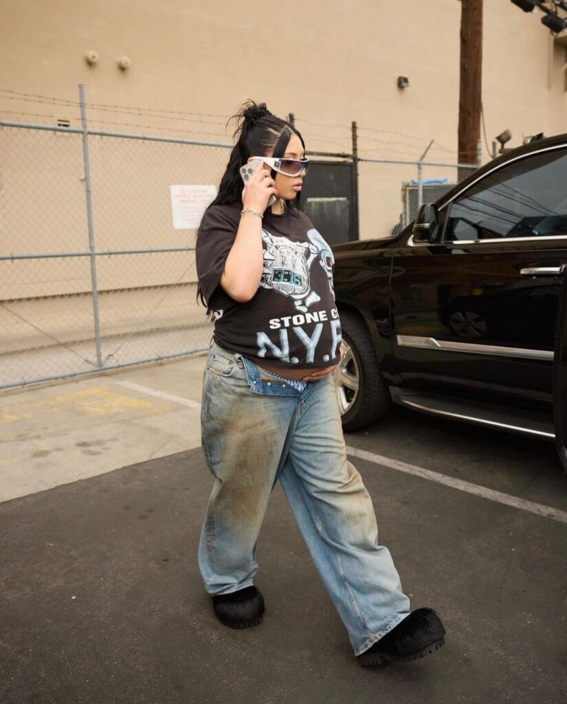 Woman wearing a black graphic t-shirt and baggy blue jeans in a parking lot