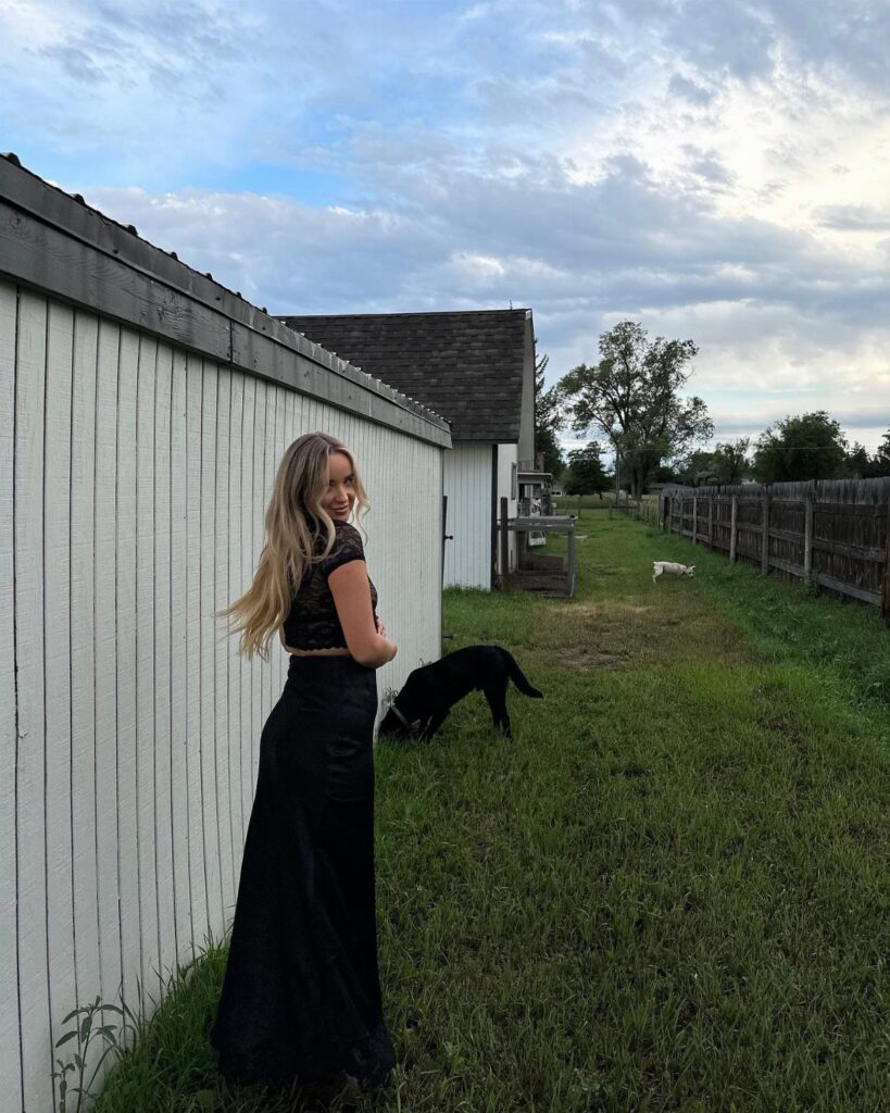 Woman wearing a black crop top and long black maxi skirt in a field
