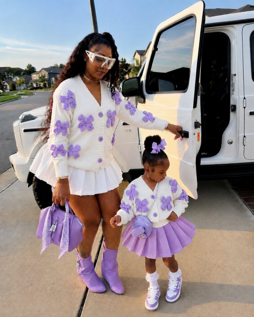 Woman and young girl wearing matching white and purple outfits standing by a white car.