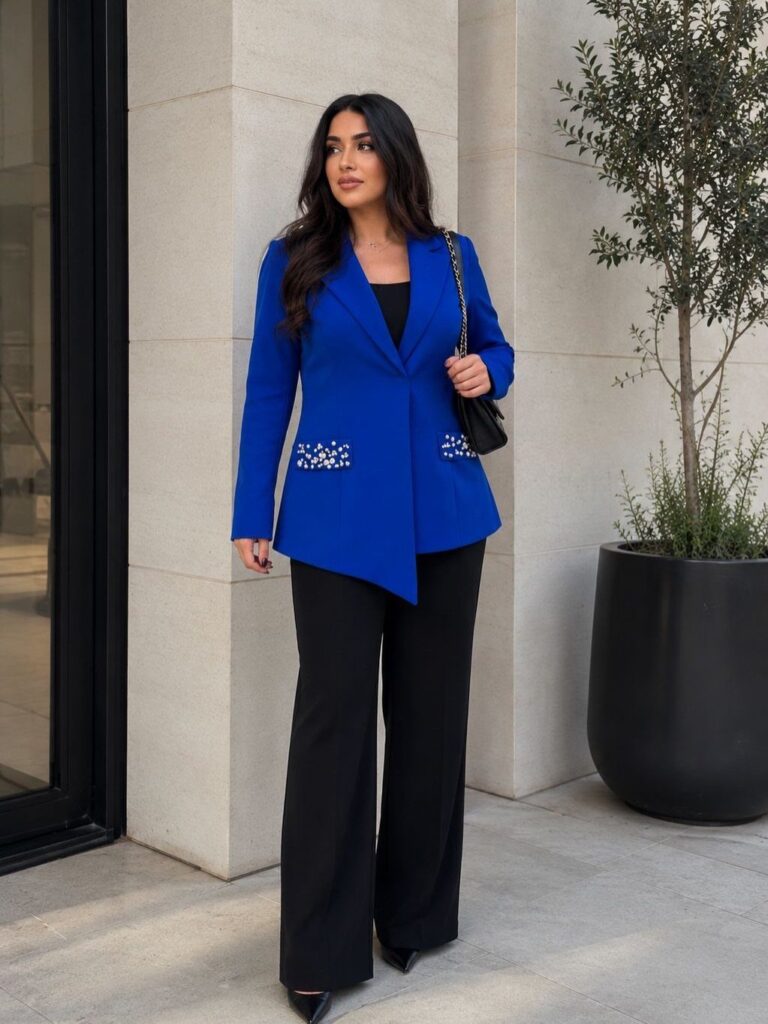 Woman wearing a royal blue blazer and black wide-leg trousers standing outdoors.
