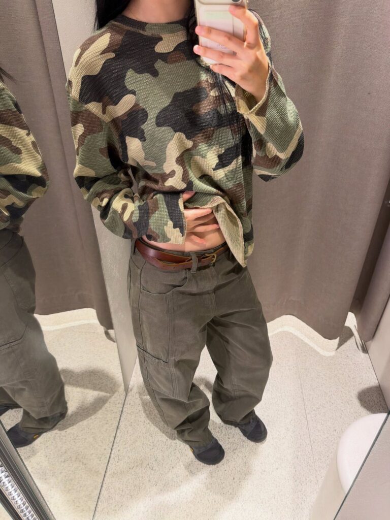 Person wearing a camouflage print top and olive green cargo pants in a mirror