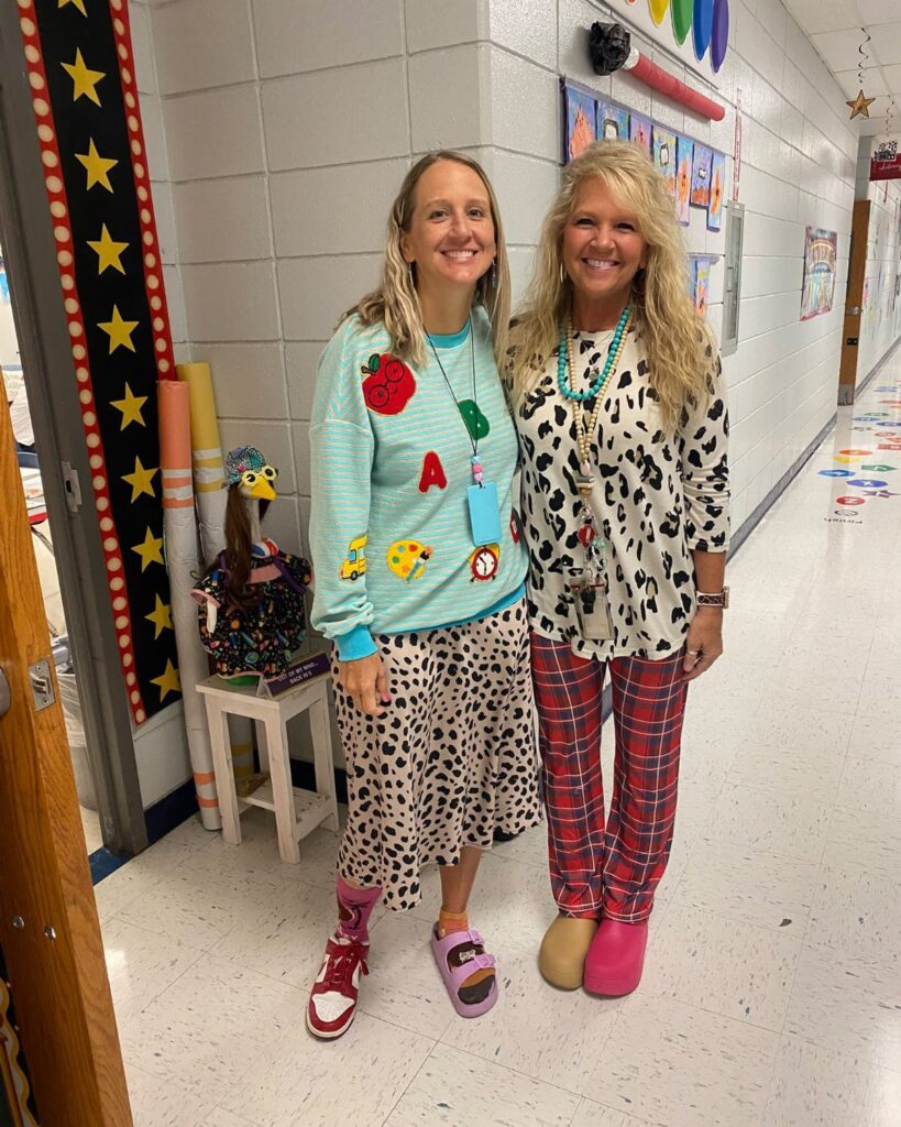 Two women in a school hallway wearing mismatched, colorful, and eclectic wacky outfits.